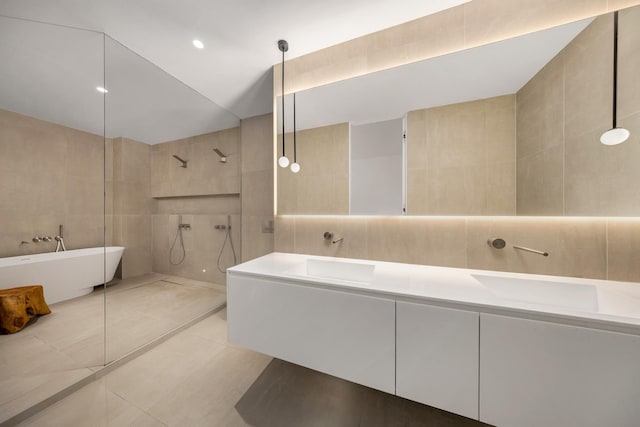 full bathroom with tile patterned flooring, tile walls, a soaking tub, double vanity, and walk in shower