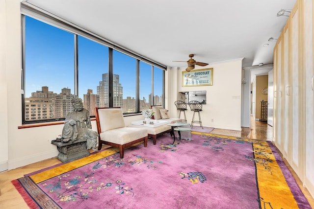 living area featuring baseboards, a ceiling fan, a city view, and wood finished floors