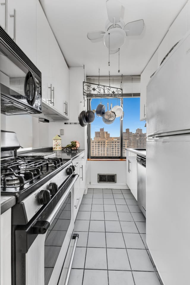 kitchen with a view of city, light tile patterned floors, stainless steel appliances, visible vents, and white cabinets