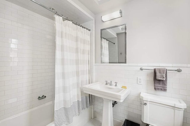 bathroom with tile walls, shower / bathtub combination with curtain, and toilet