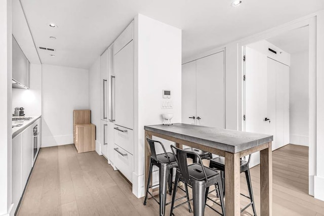 kitchen featuring oven, white cabinets, and light hardwood / wood-style flooring