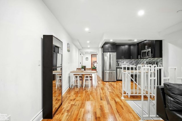 kitchen featuring stainless steel appliances, light hardwood / wood-style floors, and backsplash