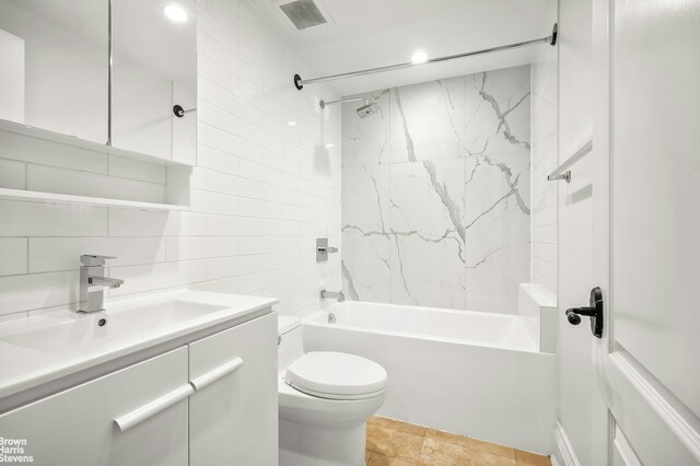 full bathroom with toilet, tasteful backsplash, tiled shower / bath, tile walls, and vanity