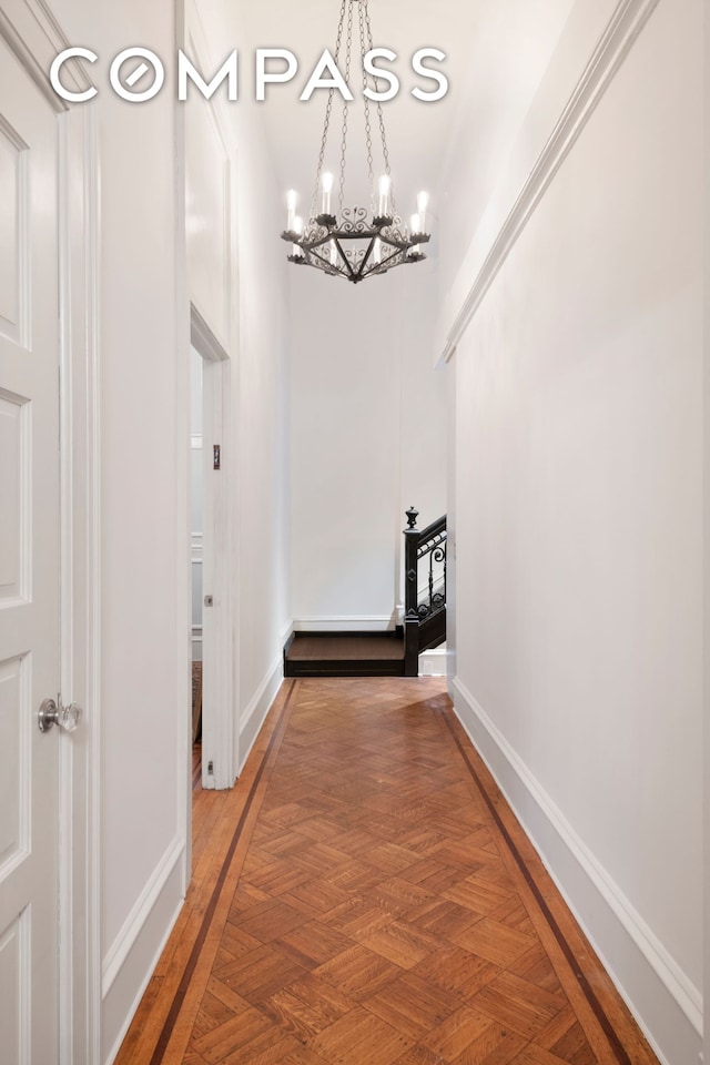 corridor with an inviting chandelier and baseboards