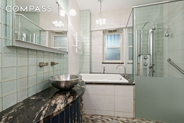 bathroom with tile walls, sink, and independent shower and bath