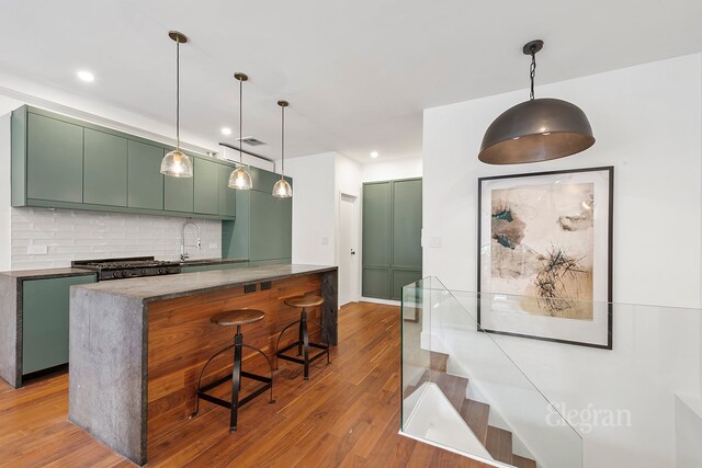 kitchen featuring wood-type flooring, sink, a breakfast bar area, decorative backsplash, and kitchen peninsula