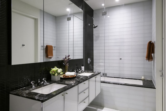 bathroom featuring double vanity, tile walls, a sink, and decorative backsplash