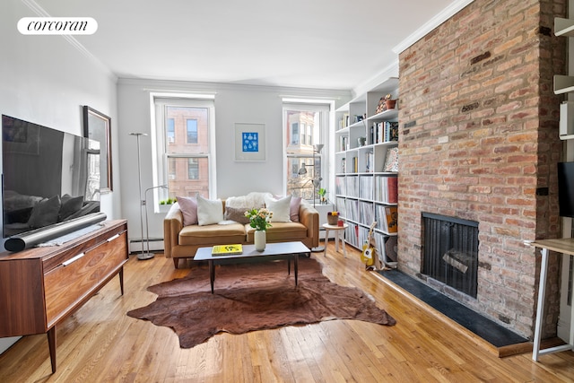 living room with crown molding, a brick fireplace, light hardwood / wood-style flooring, and a baseboard heating unit