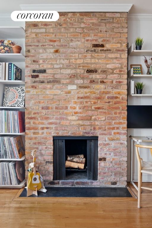 details with built in shelves, a fireplace, ornamental molding, and wood-type flooring