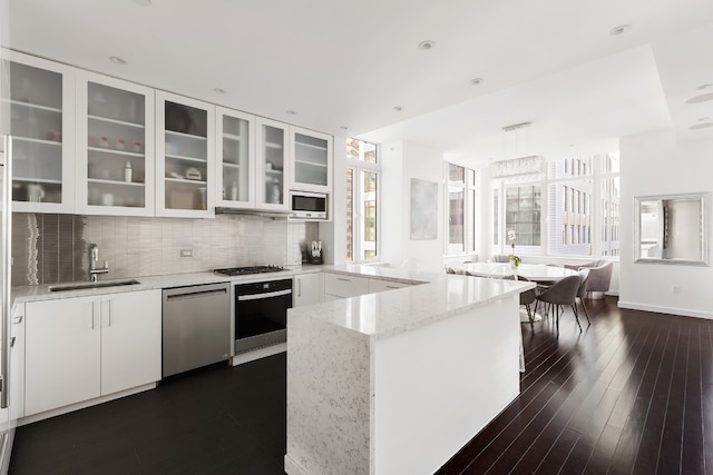 kitchen featuring white cabinetry, sink, hanging light fixtures, stainless steel appliances, and light stone countertops