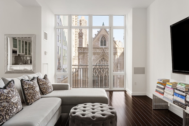 living area featuring visible vents, baseboards, a wealth of natural light, and dark wood-type flooring