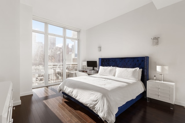 bedroom with wood-type flooring, a wall of windows, baseboards, and access to exterior
