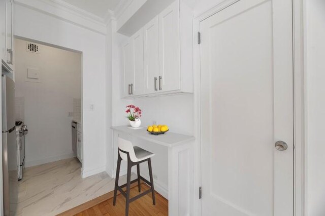 kitchen featuring crown molding, white cabinets, and light hardwood / wood-style floors