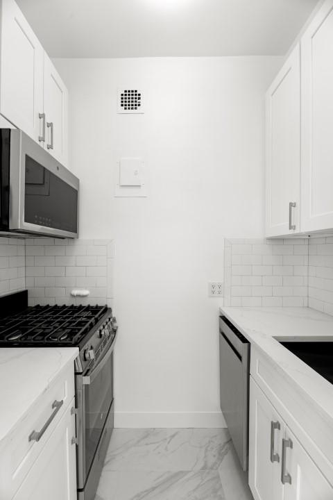 kitchen with light stone counters, tasteful backsplash, stainless steel appliances, and white cabinets