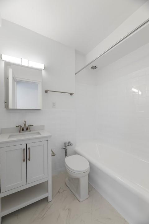 full bathroom featuring vanity, shower / washtub combination, tile walls, and toilet