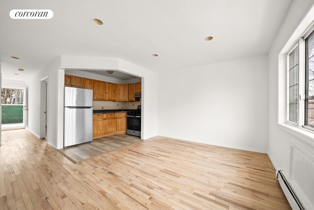 kitchen with a baseboard heating unit, stainless steel appliances, and light wood-type flooring