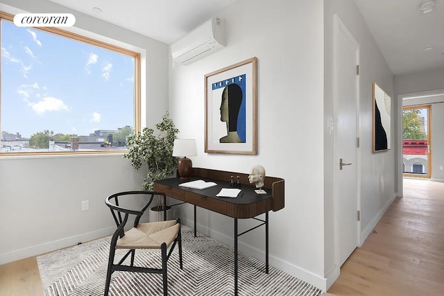 office featuring baseboards, a wall unit AC, visible vents, and light wood finished floors