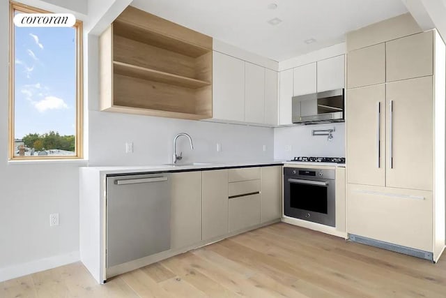 kitchen featuring appliances with stainless steel finishes, sink, and light hardwood / wood-style flooring