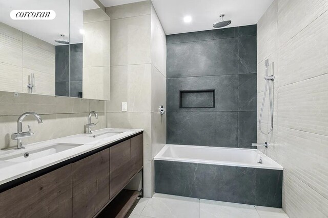 bathroom with a combined bath / shower with rainfall shower, visible vents, tile patterned floors, a sink, and tile walls