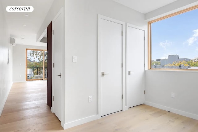 corridor with visible vents, light wood-type flooring, and baseboards