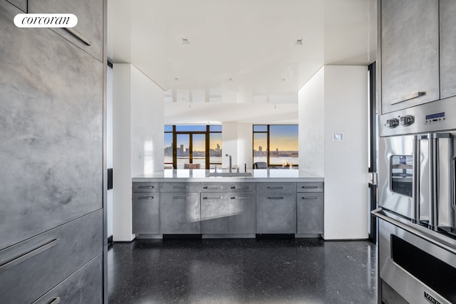 kitchen featuring stainless steel double oven, a sink, gray cabinetry, and dark speckled floor