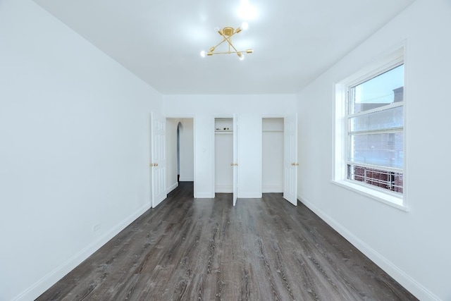 unfurnished bedroom featuring dark hardwood / wood-style flooring and a chandelier