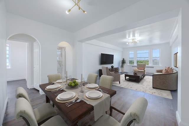 dining room featuring a chandelier, radiator heating unit, arched walkways, and wood finished floors