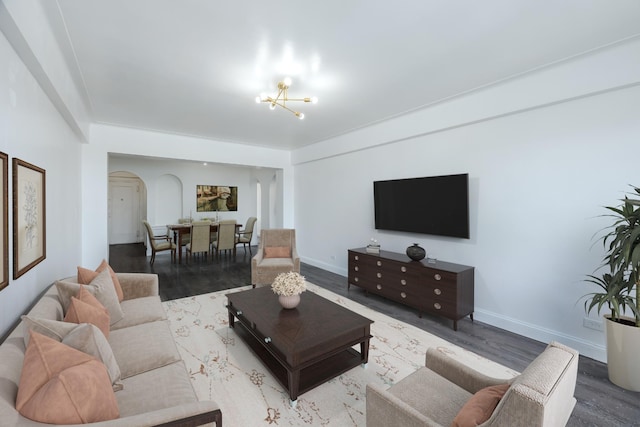 living room featuring an inviting chandelier, baseboards, wood finished floors, and arched walkways
