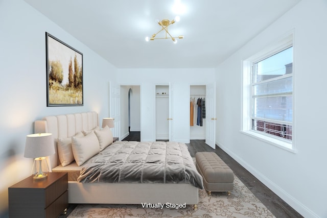 bedroom featuring wood finished floors, baseboards, and an inviting chandelier