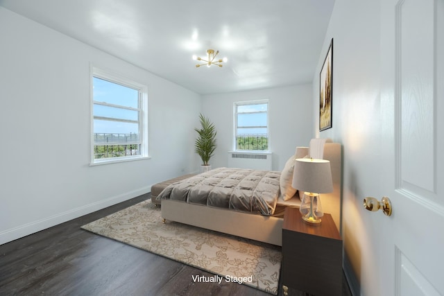 bedroom featuring radiator heating unit, baseboards, wood finished floors, and a chandelier