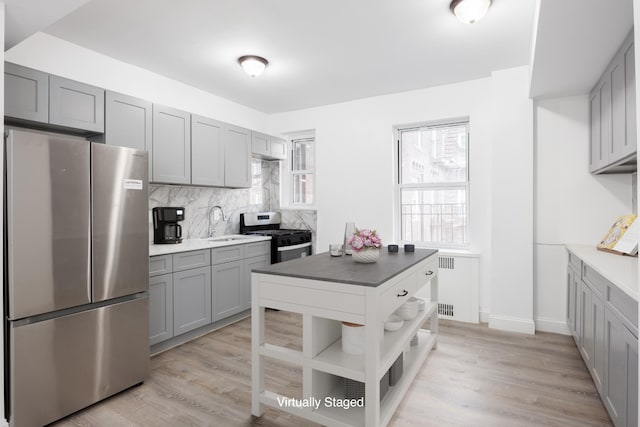 kitchen with gas range, radiator heating unit, gray cabinets, and freestanding refrigerator