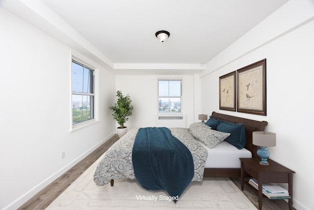 bedroom with multiple windows, wood finished floors, and baseboards