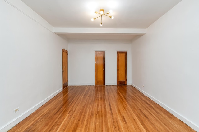 unfurnished bedroom featuring a notable chandelier, light wood-style flooring, baseboards, and beamed ceiling