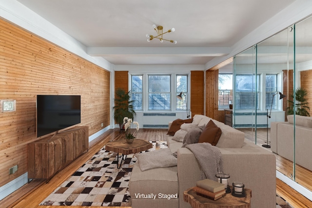 living room with wood finished floors, radiator, wood walls, a notable chandelier, and beam ceiling