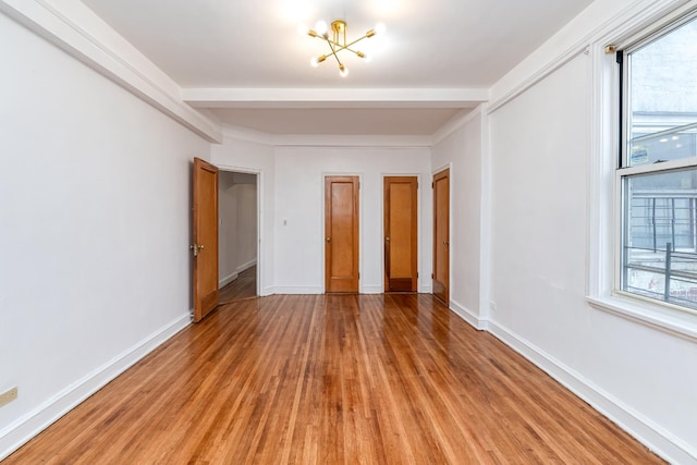 unfurnished bedroom with multiple windows, beam ceiling, and baseboards