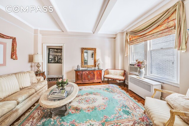 sitting room with hardwood / wood-style flooring, radiator heating unit, beamed ceiling, and a healthy amount of sunlight