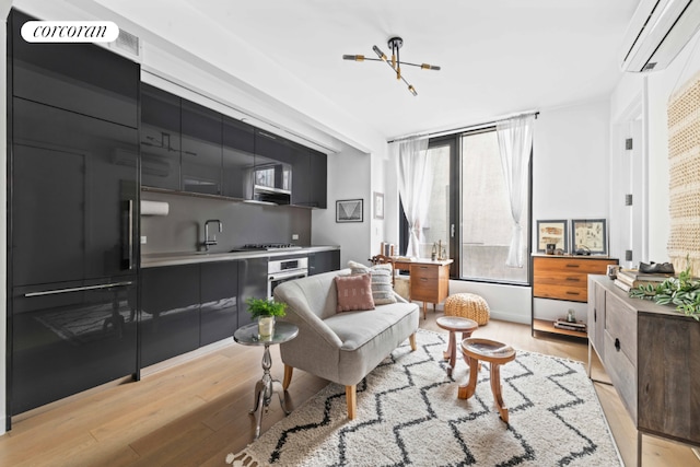 living area featuring light wood-type flooring and a wall unit AC