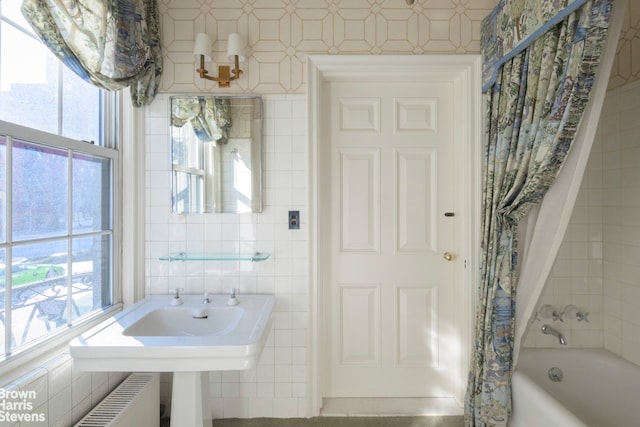 bathroom with radiator heating unit, plenty of natural light, and tile walls