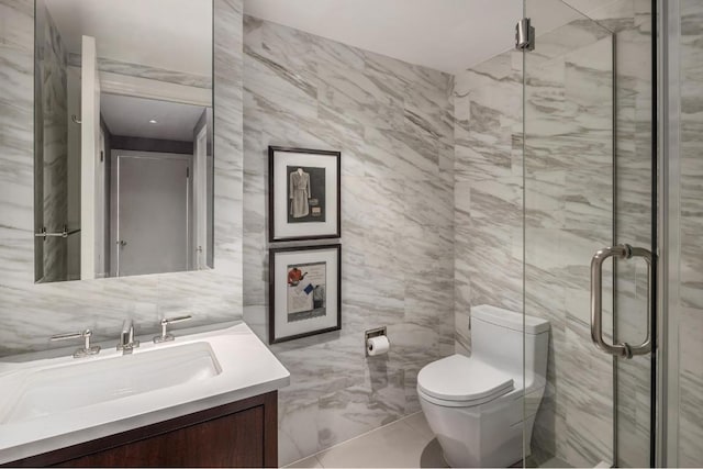 bathroom with a shower with door, vanity, tile walls, and toilet