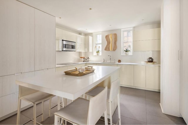 kitchen featuring a center island, a breakfast bar area, white cabinets, and light tile patterned floors