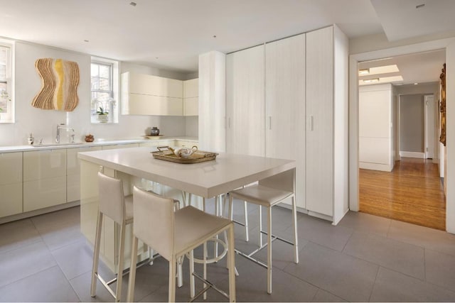 kitchen featuring a kitchen breakfast bar, sink, a kitchen island, and light tile patterned floors