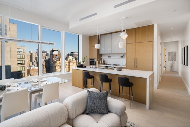 kitchen with light countertops, stainless steel oven, a kitchen breakfast bar, modern cabinets, and open floor plan