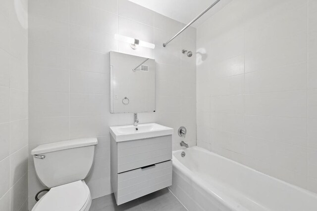 full bathroom featuring vanity, tile walls, toilet, and tiled shower / bath