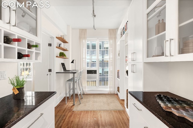 kitchen featuring hardwood / wood-style flooring, white cabinetry, and dark stone countertops