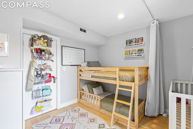 bedroom with a crib and wood-type flooring