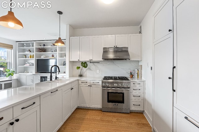 kitchen featuring stainless steel range, decorative light fixtures, sink, and white cabinets