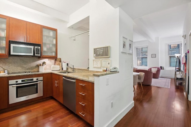 kitchen with sink, stainless steel appliances, light stone counters, dark hardwood / wood-style flooring, and decorative backsplash