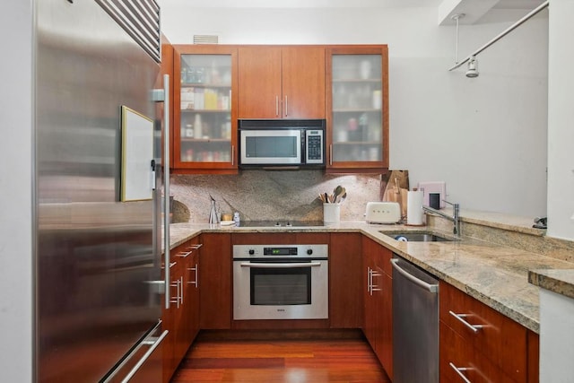 kitchen with appliances with stainless steel finishes, dark hardwood / wood-style floors, sink, backsplash, and light stone counters