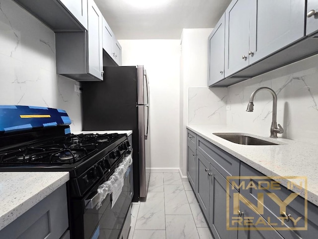 kitchen featuring marble finish floor, gray cabinets, black gas stove, a sink, and light stone countertops