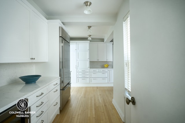 kitchen featuring white cabinetry, high end fridge, light stone counters, and light wood-type flooring